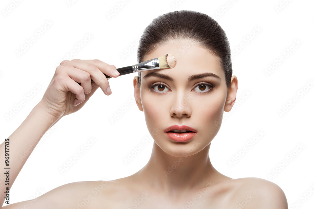 Beautiful girl applying foundation with brush