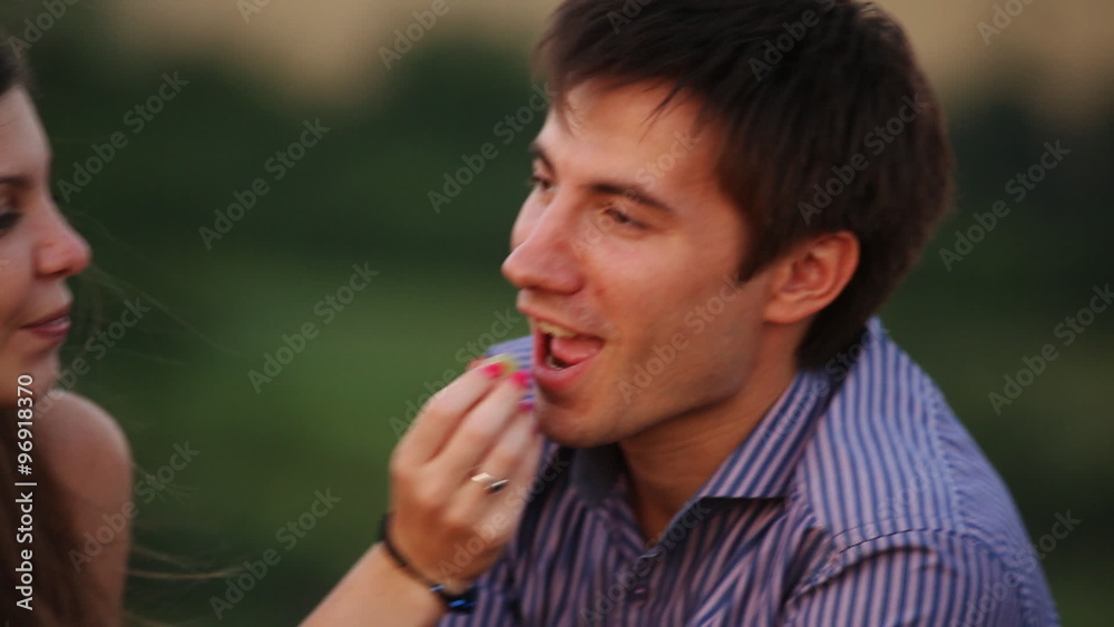Man feeding woman grapes at a picnic Man feeding woman grapes at a picnic