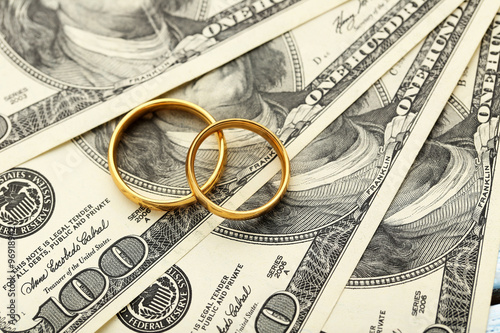 Golden wedding rings on one hundred dollars bill background