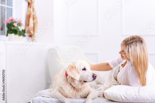 Caring woman lying on bed with her dog 