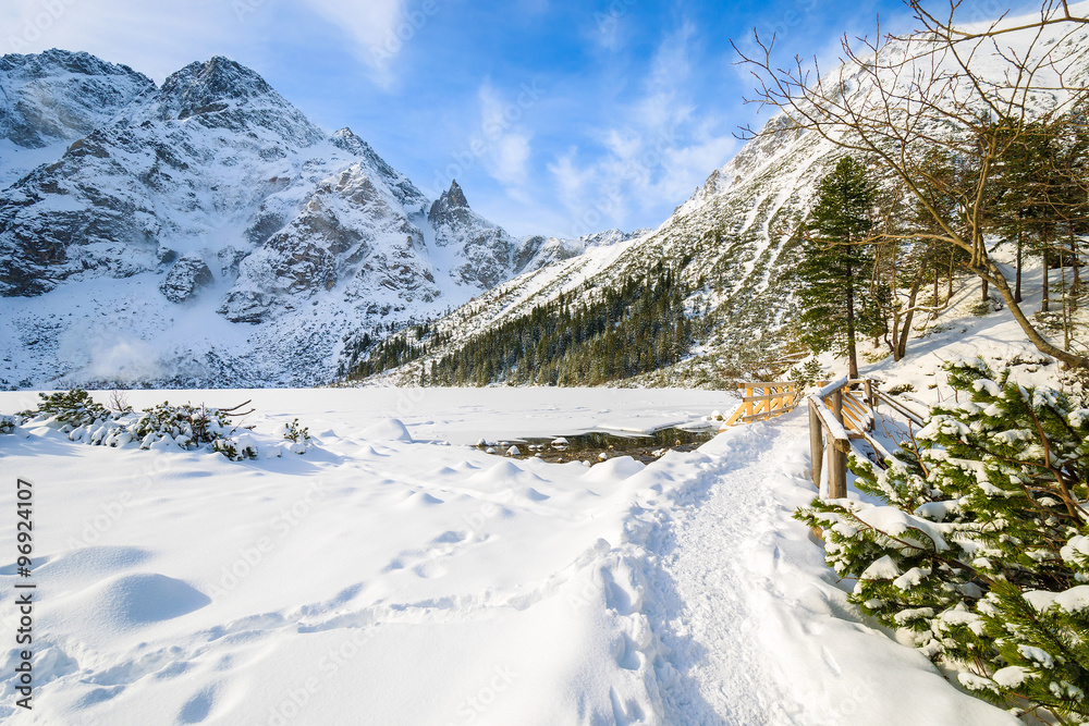 Hiking path in fresh snow along frozen Morskie Oko lake in winter, Tatra Mountains, Poland