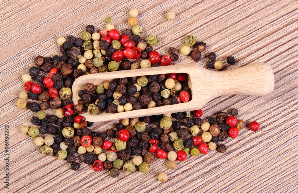 Fresh colored pepper with spoon on wooden background