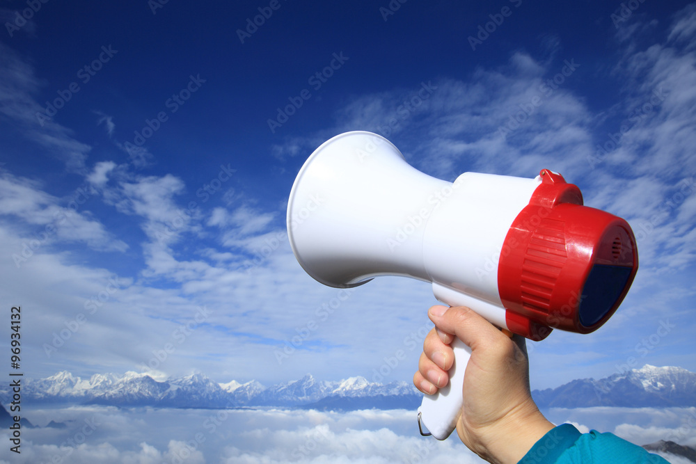 hand hold loudspeaker to blue sky on mountain peak hand hold loudspeaker to blue sky on mountain peak