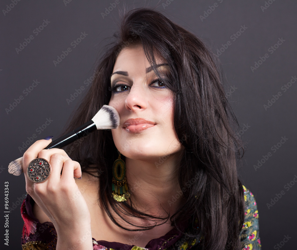 Obraz premium Beautiful brunette apply makeup in bright clothes. Portrait of a well-groomed woman. Attractive brunette with make-up brush 