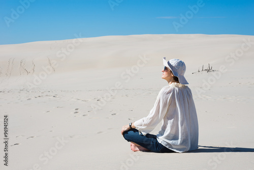 Woman sitting on sand and looking at sky