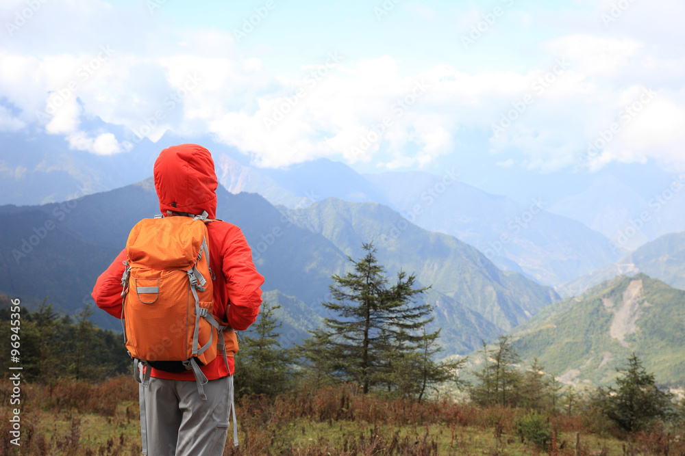 young determined woman backpacker hiking on mountain peak young determined woman backpacker hiking on mountain peak