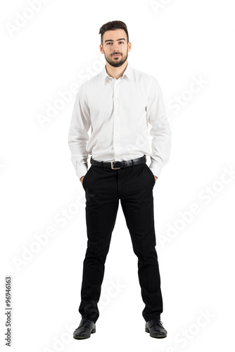 Confident elegant business man with hands in pockets looking at camera.  Full body length portrait isolated over white studio background. © sharplaninac