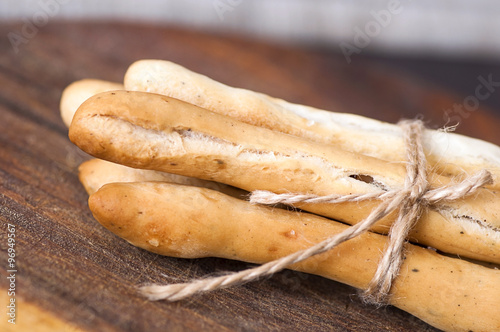 Salted Italian grissini on wooden cutting board close up