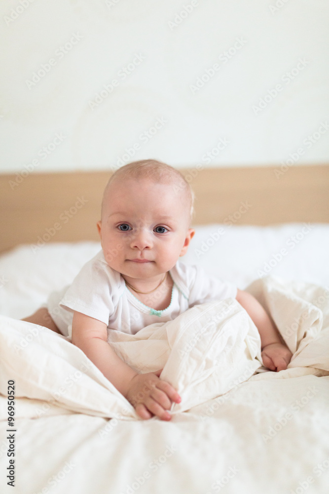 Baby girl on a bed on a light background