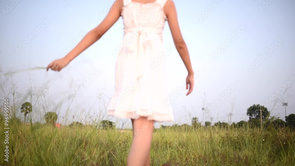 Young Asian girl walk on the dry grass field under daylight Young Asian girl walk on the dry grass field under daylight
