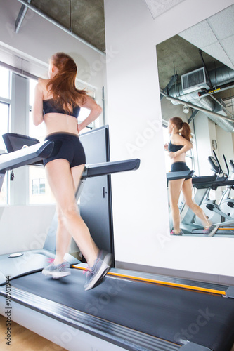 strong woman running on treadmill in gym