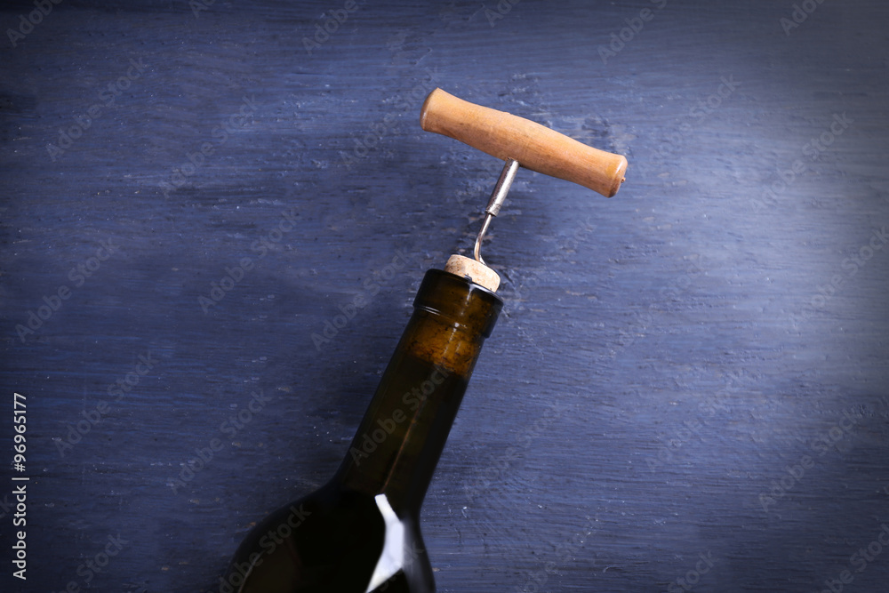 Corkscrew and wine bottle on blue wooden background