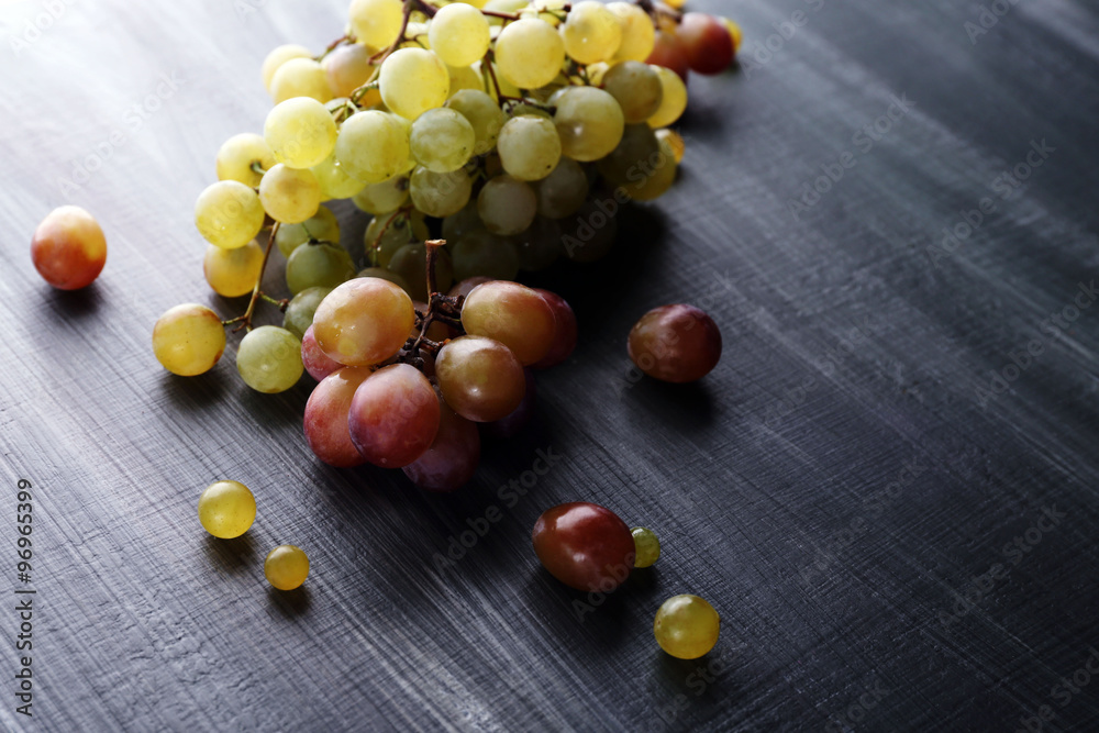 Juicy green and purple grapes, on wooden background