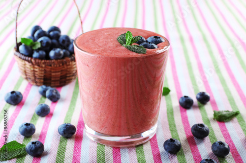 A glass of fresh cold smoothie with berries, on lined tablecloth background
