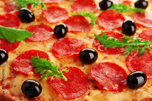 Pepperoni pizza with olives and arugula, close-up