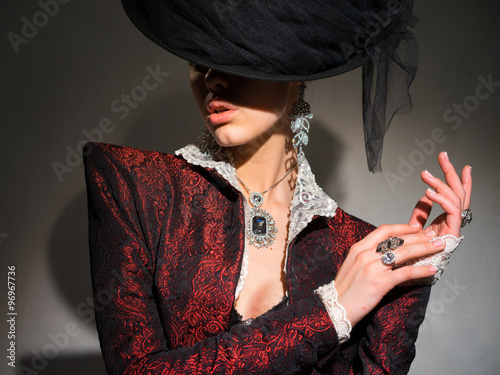Obraz na plátně Portrait of a woman in a red jacket and jewelry on the hand