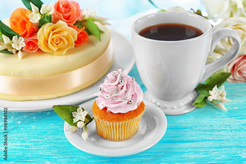 Cake with sugar paste flowers and cupcake, on light background Cake with sugar paste flowers and cupcake, on light background