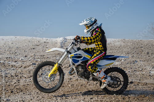 MX rider on a motorcycle starts to move on a snowy road with a raised front wheel