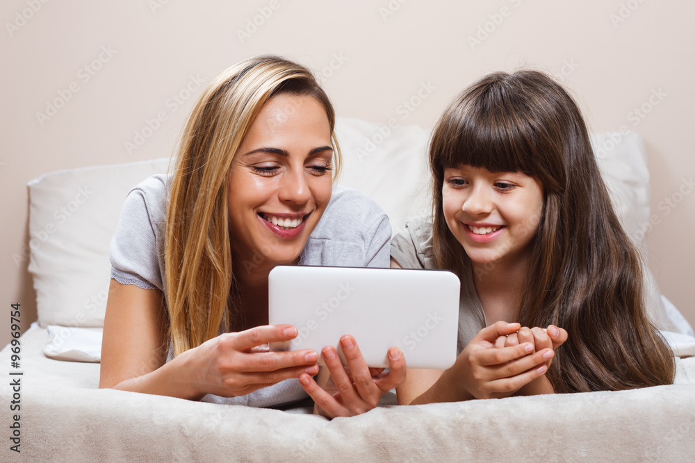Mother and daughter using digital tablet in bed Mother and daughter using digital tablet in bed