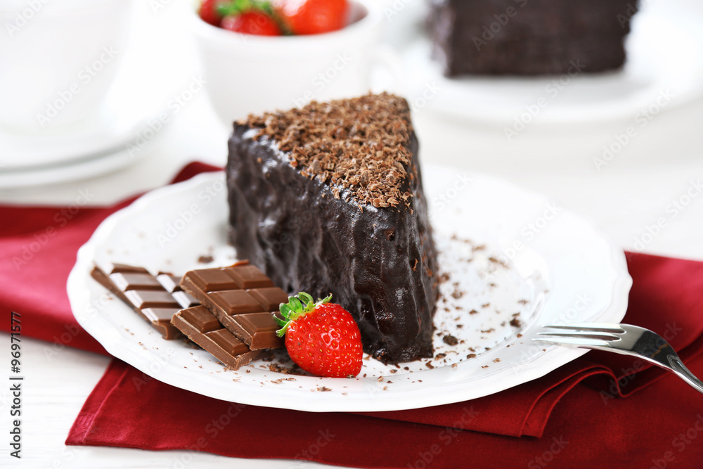 Chocolate cake with chocolate cream and fresh strawberries on plate, on light background