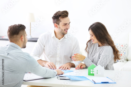 Happy family with estate agent, in bright office