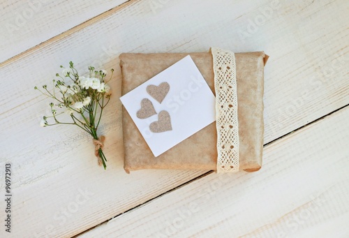 Handcrafted gift box wrapped in parchment paper, decorated lace ribbon, paper hearts, tender gypsophila flowers