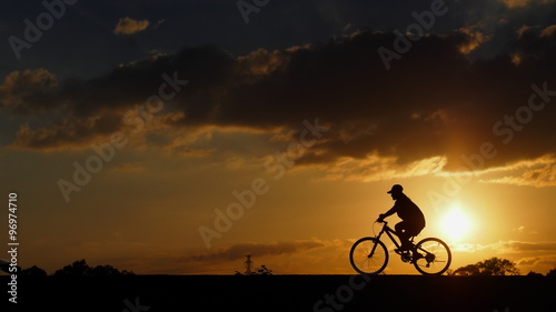 A woman rides a bicycle on the road when sunset: silhouette photo