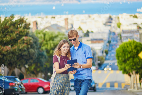 Romantic couple of tourists using tablet in San Francisco, California, USA