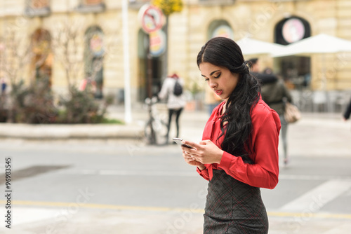 Hispanic stewardess in urban background looking at her mobile ph © javiindy