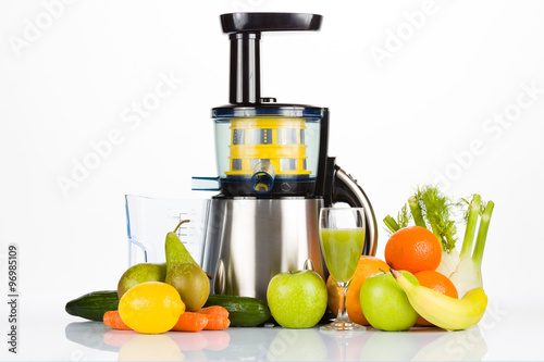 Slow juicer with fruit, vegetables and a glass of fresh juice on white table with white background, for a healthy lifestyle