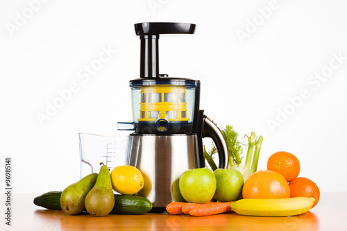 Slow juicer with fruit, vegetables on wooden table with white background, for a healthy lifestyle
