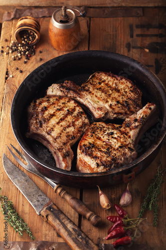 Grilled pork chop with spices in a frying pan