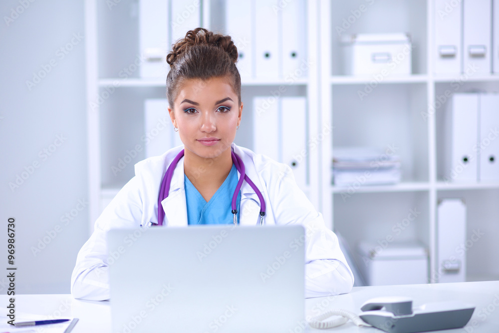 Female doctor sitting on the desk and working a laptop in hospital Female doctor sitting on the desk and working a laptop in hospital