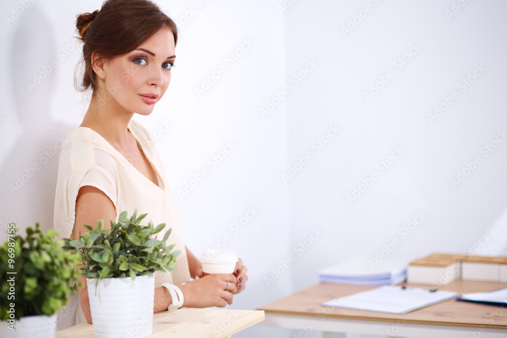 Attractive young businesswoman standing near desk in the office Attractive young businesswoman standing near desk in the office