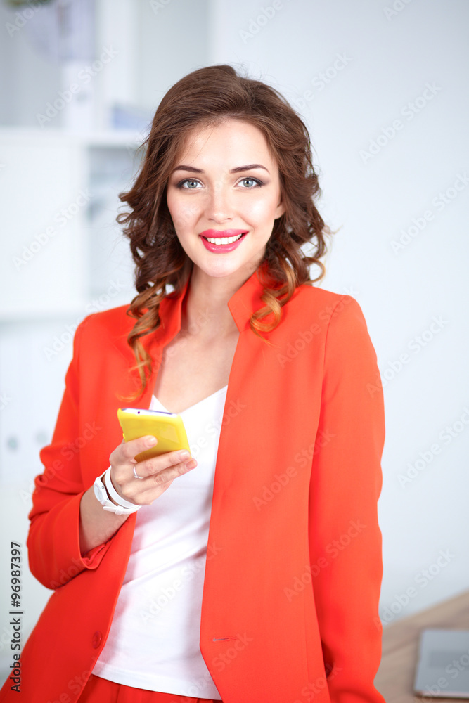 Beautiful businesswoman using cell phone standing in office Beautiful businesswoman using cell phone standing in office