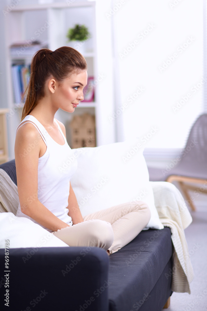 Woman sitting on the couch in living room and smiling Woman sitting on the couch in living room and smiling