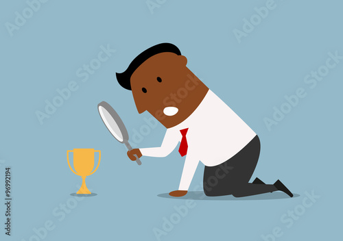 Businessman looking at small trophy with magnifier