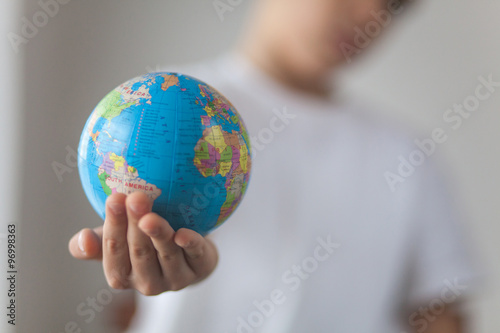 Boy holding toy globus in his hand. Day natural window light