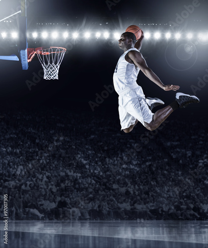 Basketball Player scoring an athletic, amazing slam dunk in a professional basketball game © Brocreative