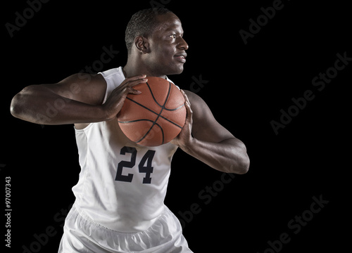 African American Basketball Player portrait holding a ball. Black background
