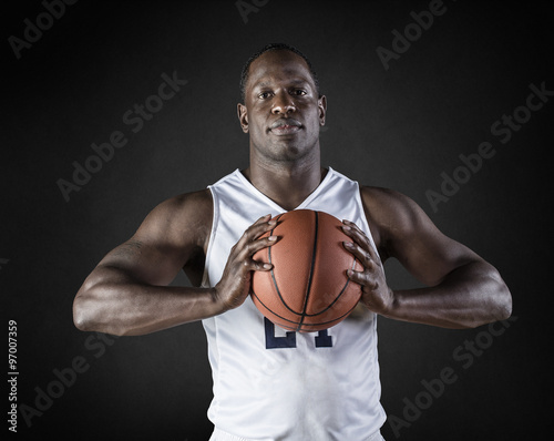 African American Basketball Player portrait holding a ball. Black background © Brocreative