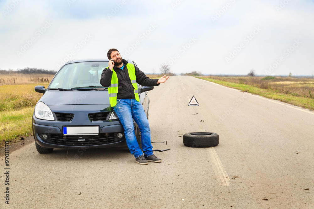 Man calling for a tow truck when his car broke down by the road side