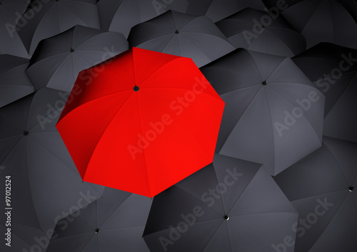 Top view on unique red umbrella among many dark ones.