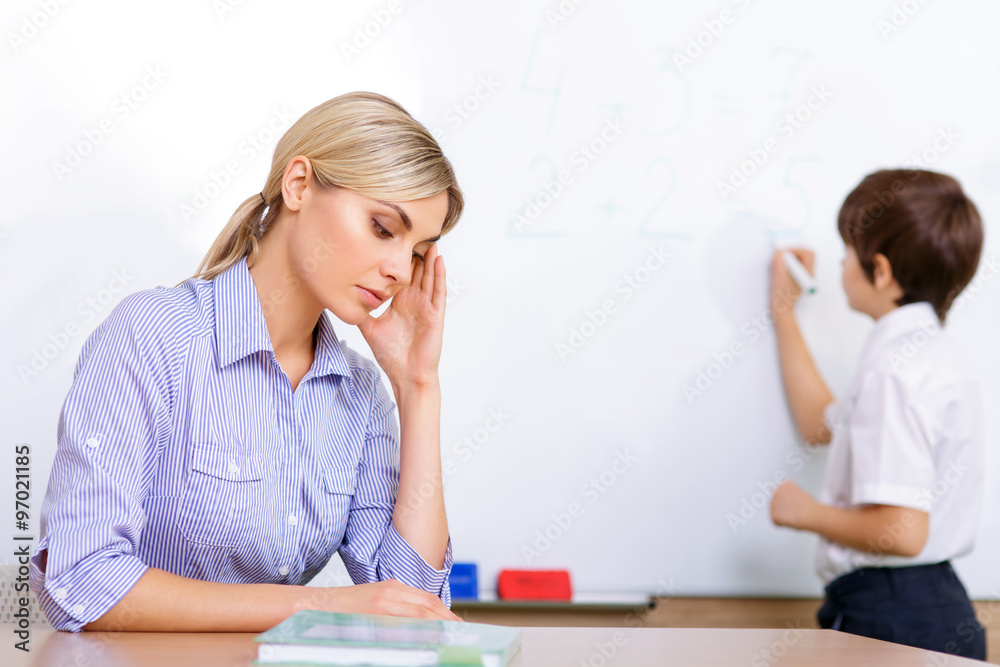 Teacher is sitting at the desk during lesson. Teacher is sitting at the desk during lesson.
