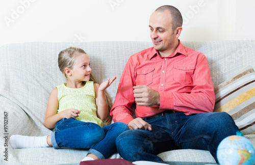 Portrait of father and little girl discussing something indoors