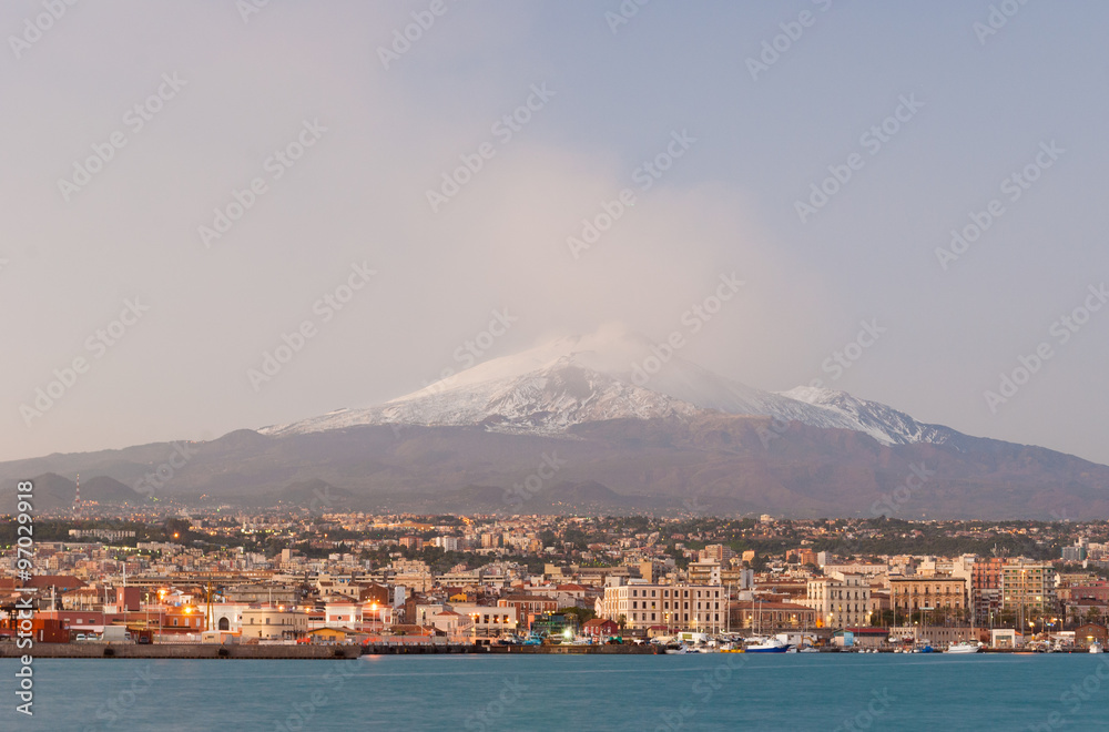 Skyline of Catania with snowy volcano Etna in background during the winter after the sunset