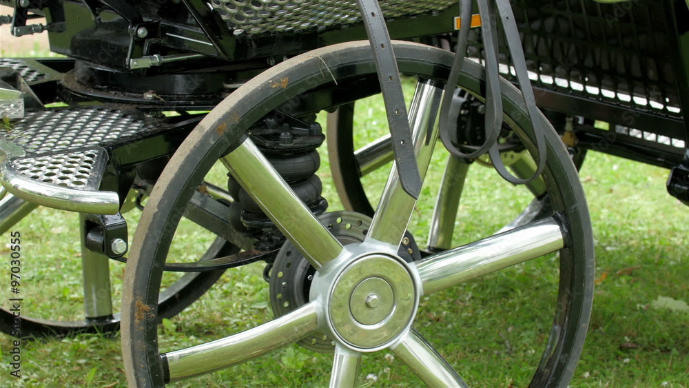 The metal wheels of the carriage in the grass. This the modern carriage being handled by the horses in Tartu The metal wheels of the carriage in the grass. This the modern carriage being handled by the horses in Tartu