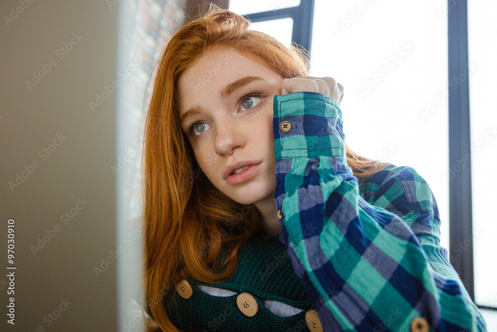 Concentrated woman with red hair hugging knitted cushion Concentrated woman with red hair hugging knitted cushion