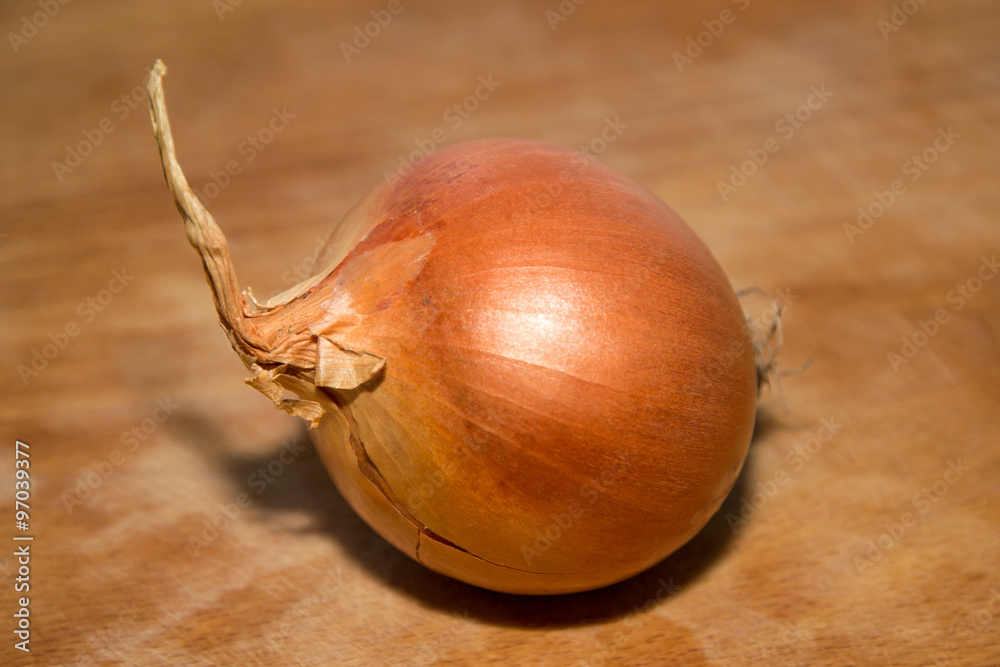 A whole onion on a wooden board.
