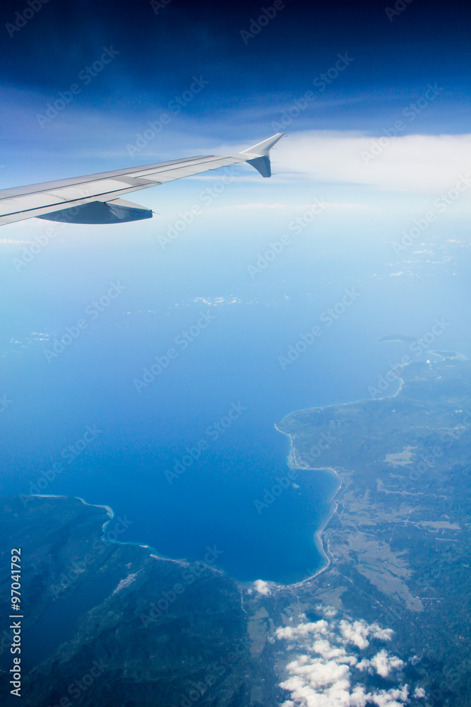 land and ocean bird's eye view shot with plane wing